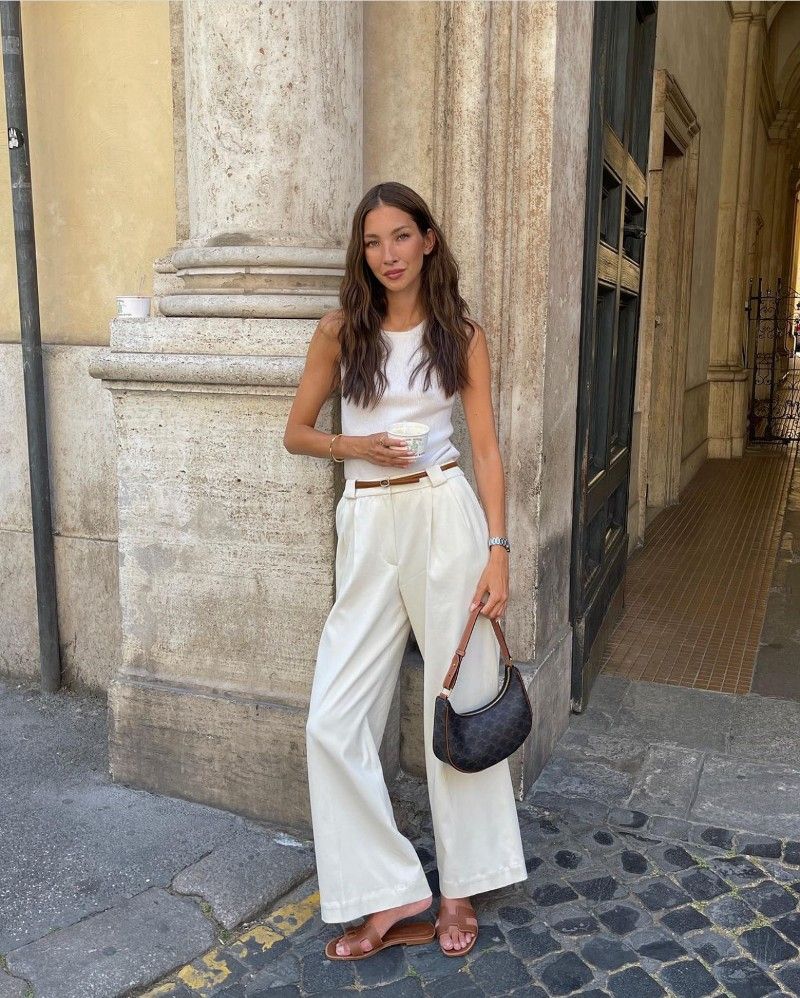 Felicia Akerstrom in a white tank top and white pleated trousers